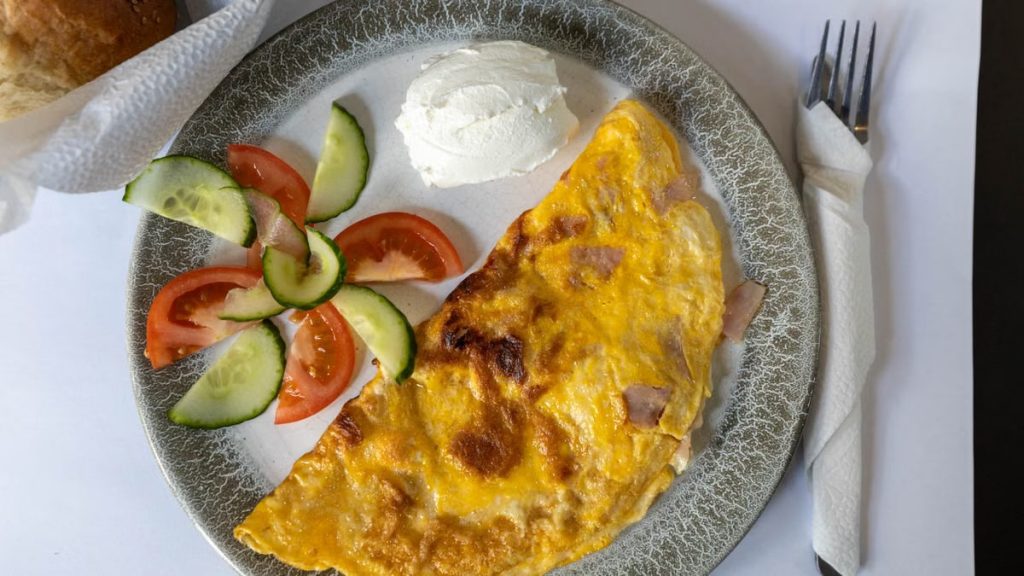 Top view of an omelette with cucumbers and tomatoes, perfect breakfast setting.